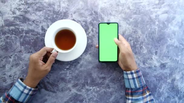 shora pohled na člověka rukou pomocí chytrého telefonu a pití čaje  - Záběry, video
