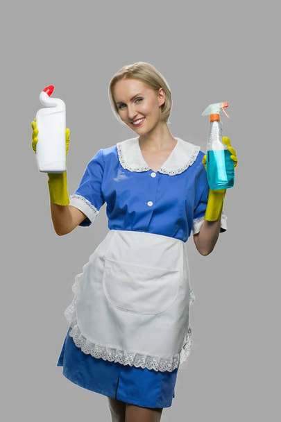 Mulher empregada segurando duas garrafas de detergente. - Foto, Imagem