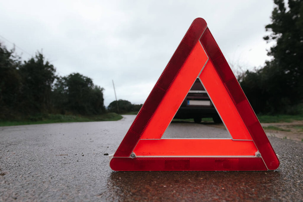 Egy autó piros háromszöge az úton. Autóriasztó háromszög. Autóbaleset rossz időben. - Fotó, kép