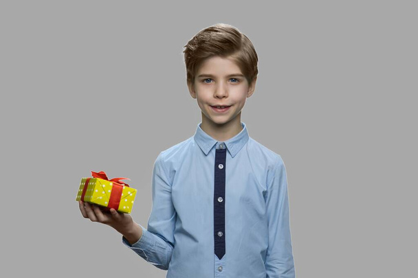 Junge hält Geschenkbox auf grauem Hintergrund. - Foto, Bild