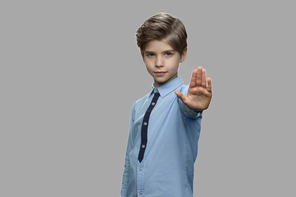 Pequeño niño mostrando gesto de stop sobre fondo gris. - Foto, imagen