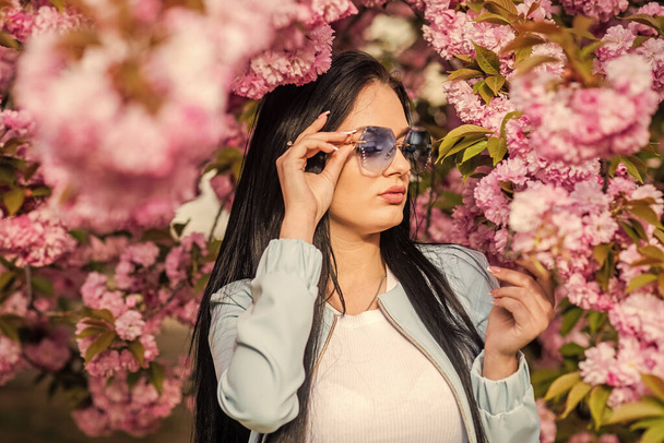 Enjoying the spring sunshine. Happy easter. sexy girl enjoy sakura blossom. woman in cherry bloom. Woman on nature background. beautiful young lady in the garden of cherry blossoms. 8 march - Foto, afbeelding