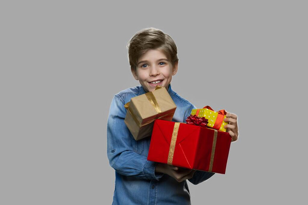 Cute smiling boy holding gift boxes. - Foto, imagen