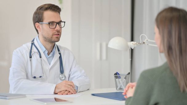Männlicher Arzt diskutiert mit Patient über Krankenakte  - Foto, Bild