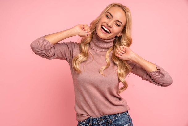 Beautiful young woman wearing sweater standing isolated over pink background, celebrating success. - Photo, Image