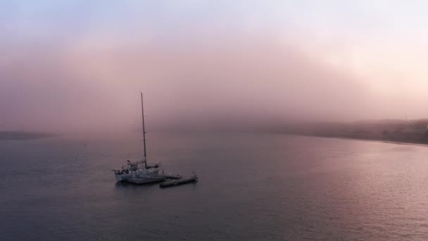 Cinematic aerial of Sailing yacht moored off coast at pink sunset or sunrise - Footage, Video