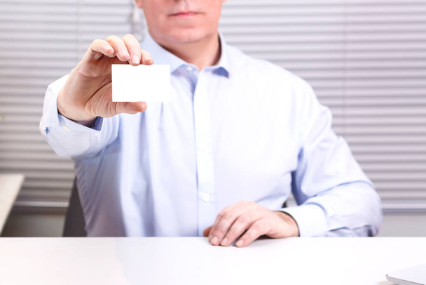 A man in the office at the computer holds a sign in his hands. Horizontal photo - Foto, immagini