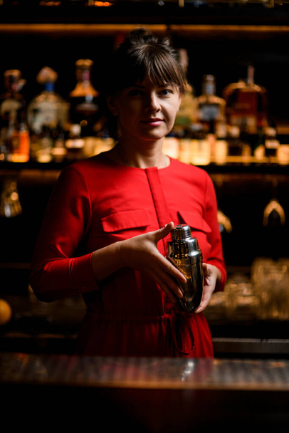view of attractive woman bartender with steel shaker in her hands - 写真・画像