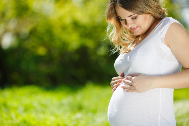 Muotokuva Terve raskaana oleva nainen istuu vihreää ruohoa
 - Valokuva, kuva