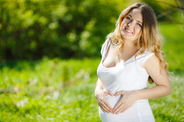 Portrait Healthy pregnant woman sitting on green grass - Photo, Image