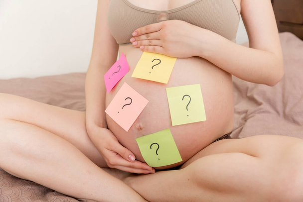 Έγκυος κοιλιά γυναίκα με ερωτηματικό. Εγκυμοσύνη και σκέψη πρόβλημα. - Φωτογραφία, εικόνα