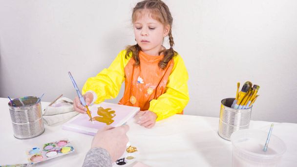 Kleines Mädchen malt mit Acrylfarbe auf Leinwand mit ihrer Mutter für ein Kunstprojekt im Fernunterricht. - Foto, Bild