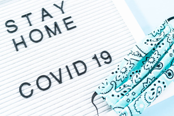 STAY HOME and COVID-19 sign on message board with a homemade face mask. - Photo, Image