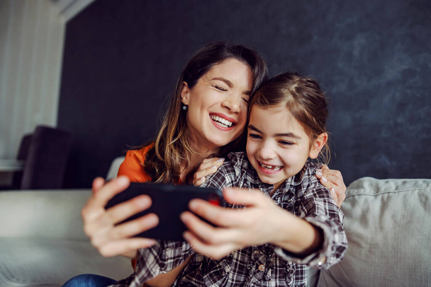 Smiling happy mother and daughter hugging and taking a selfie. Happy family having quality time together. - Photo, Image