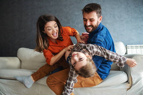 Mother and father playing with their daughter. Father holding daughter while mother tickling her. - Photo, Image