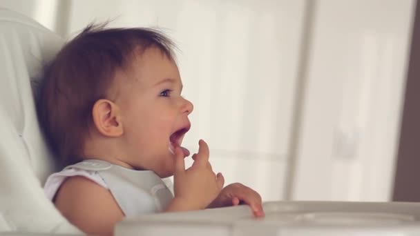 Moeders Hand geven voedsel aan haar dochtertje op kinderstoel in huis keuken - Video