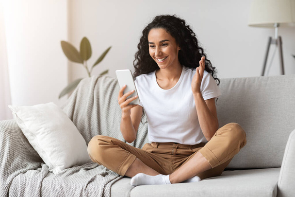 Pozitivní mladá žena sedí na gauči, mající online hovor - Fotografie, Obrázek