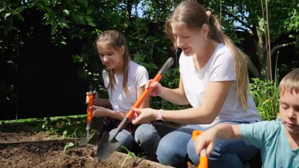 Slow motion video of adults and children digging soil at garden and planting fresh organic vegetable seedlings - Footage, Video