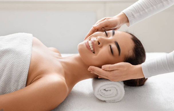 Mulher coreana sorridente no salão de spa desfrutando de relaxante massagem na cabeça - Foto, Imagem