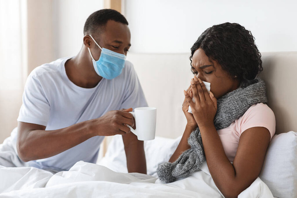 Black man in face mask take care of sick wife - Foto, imagen