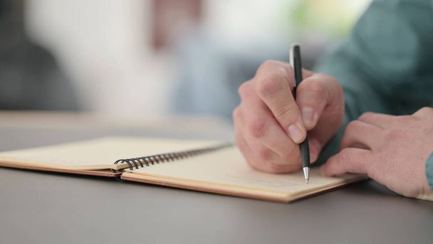 Закрыть руки человека, пишущего в тетрадке - Фото, изображение