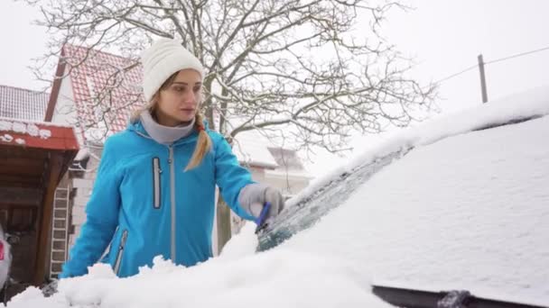 Mulher raspando gelo da janela da frente de seu carro no inverno - Filmagem, Vídeo