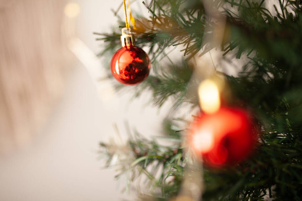 Adorno de árbol de Navidad redondo rojo en rama verde con espacio para copiar y luces de cuerda en el fondo. Tarjeta de felicitación WInter holidays. Árbol de Navidad decorado de cerca - Foto, imagen