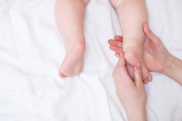 白い背景に近い女性の手に赤ん坊の足。ママと子供だ。スペースのコピー - 写真・画像