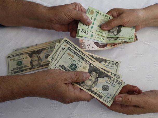 hands exchanging mexican banknotes and american dollar money - Photo, Image