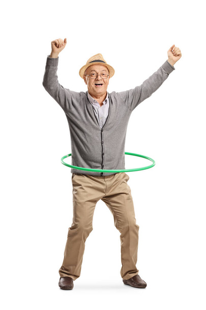 Full length portrait of an excited elderly man spinning a hula hoop isolated on white background - Фото, зображення