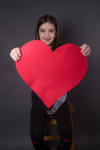 happy little girl withholding a heart - Zdjęcie, obraz