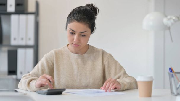 Young Indian Woman using Calculator Writing on Paper  - Photo, Image