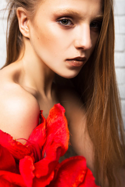 赤い花を持つ美しい若い女性の肖像画。美とファッション. - 写真・画像