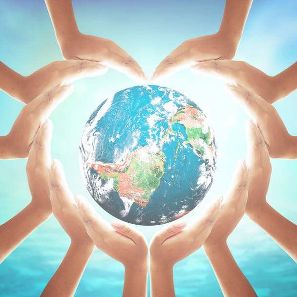 Koncepcja społecznej odpowiedzialności biznesu (CSR): Kształt serca dłoni trzymających kulę ziemską nad zamglonym błękitnym morzem i tłem nieba. Elementy tego obrazu dostarczone przez NASA - Zdjęcie, obraz
