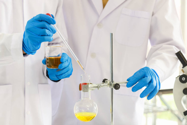 Concepto de Ciencia y Salud. Dos científicos están experimentando con productos químicos con pipetas y vasos de precipitados en un laboratorio. - Foto, imagen