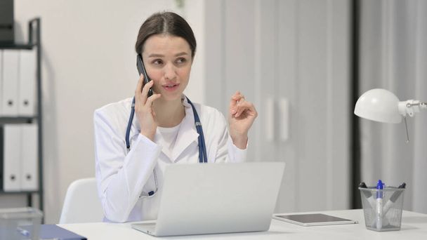 Médecin féminin avec ordinateur portable parlant sur Smartphone  - Photo, image