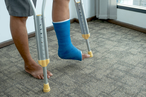 Pierna de hombre utiliza muletas para caminar después de la cirugía lesión de recuperación huesos rotos. - Foto, imagen
