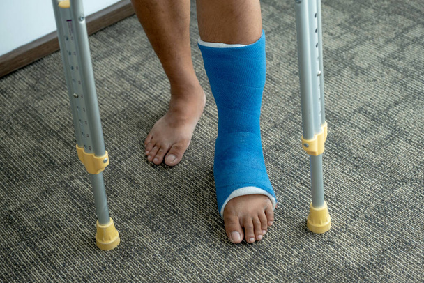 La gamba dell'uomo usa le stampelle per camminare dopo l'intervento di recupero lesioni ossa rotte. - Foto, immagini