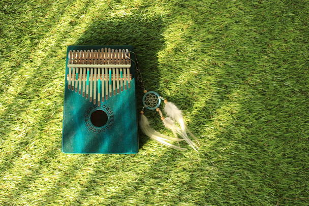 Kalimba or mbira is an African musical instrument.Traditional small Kalimba made from  wooden board with metal, play on  hands and plucking the tines with the thumbs. Instrument in room - Photo, Image