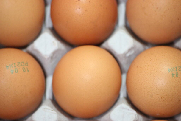 Vista de cerca con enfoque selectivo en huevos frescos de gallina de granja en un cartón de huevo o en un soporte de huevo o bandeja de papel colocada en el mercado para la venta - Foto, imagen
