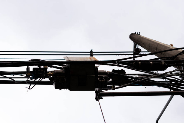 曇り空と灰色の空の都市の家の光のための電気ケーブルのシルエット - 写真・画像