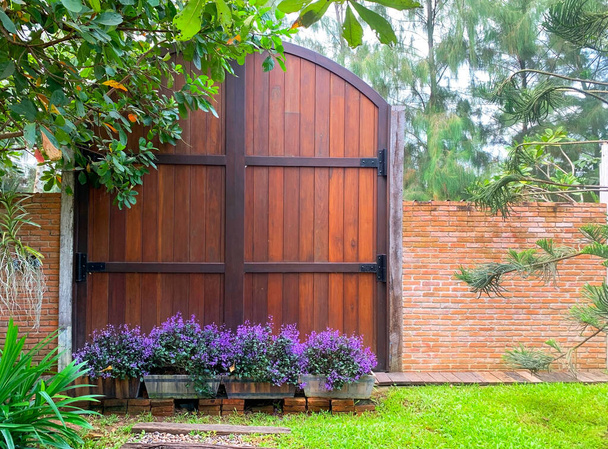 Деревянная дверь качается на большой черной стальной раме в саду. Идеи для домашнего дизайна и декора. - Фото, изображение