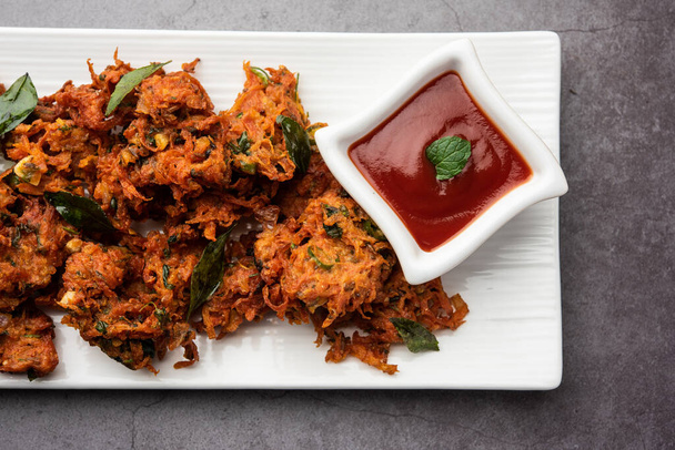 Carrot Fritters or Gajar ke pakore or pakode or bajji or bhaji, Indian snack served in a plate with tomato ketchup - Photo, Image