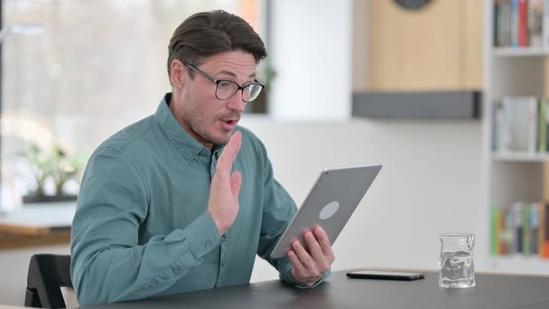 Middle Aged Man Talking on Video Chat on Tablet  - 写真・画像