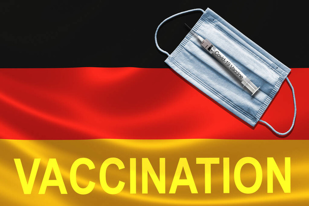 Концепция вакцинации COVID-19 в Германии с применением противомаскировочной и шприцевой вакцины на немецком флаге. - Фото, изображение