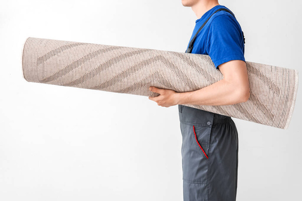 Worker with rolled carpet on white background - Foto, afbeelding