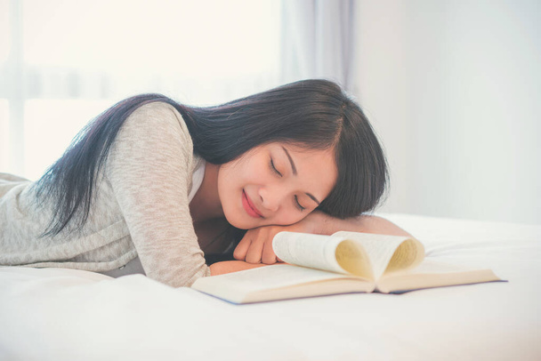 Hermosa mujer durmiendo en la cama durmiendo después de leer un libro durante la noche. - Foto, imagen