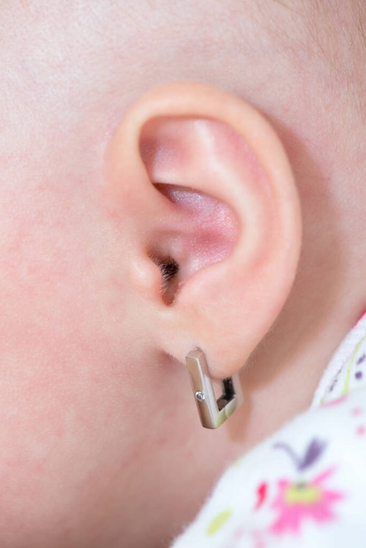 Primer plano de una oreja de bebé con pendiente - Foto, imagen