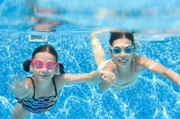 Children swim in swimming pool underwater, little active girls have fun under water, kids fitness and sport on active family vacation - Foto, Imagem