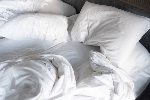Messy κρεβάτι, λευκό μαξιλάρι με κουβέρτα ξαπλωμένη στο κρεβάτι unmade, oversleeping έννοια - Φωτογραφία, εικόνα